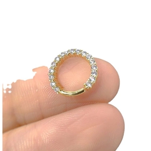 Golden micro-inlaid zircon nose ring septum clicker shown between fingers in a close-up shot