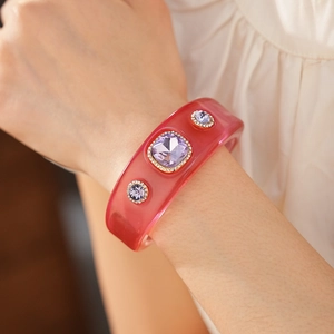 Detail of pink resin open bangle with purple crystals in gold-toned vintage settings