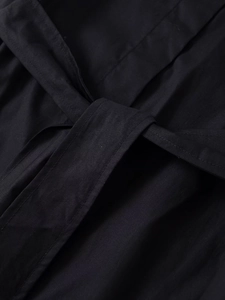 Close-up of black cargo shirt featuring detailed waist tie knot and fine fabric texture