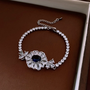 Détail macro du bracelet argenté orné d'un zircon bleu ovale et de motifs de fleurs