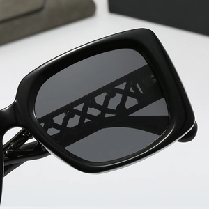 Detail of square black sunglasses showing woven chain temple design and dark lenses