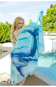 Microfiber beach towel featuring a blue watercolor whale print by a sunny poolside