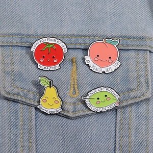 Detail of four cute fruit badges including tomato and peach pins on a denim jacket