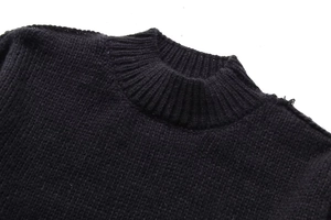 Détail d'un pull noir en maille épaisse montrant le col montant et les coutures de qualité