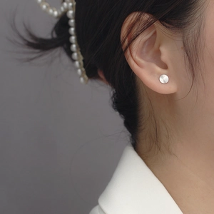 Close-up of S925 sterling silver circular stud earring with radial CD texture on ear