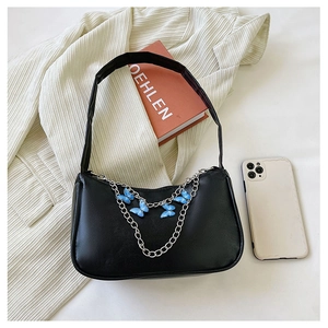 Close-up of black leather underarm bag featuring silver chains and blue butterfly charms