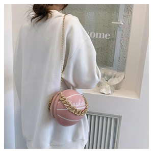 Lifestyle shot of pink basketball-shaped crossbody bag with gold chain and Basket print
