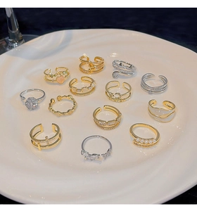 Flat lay of thirteen assorted luxury rings with zircon and pearls in a ceramic tray