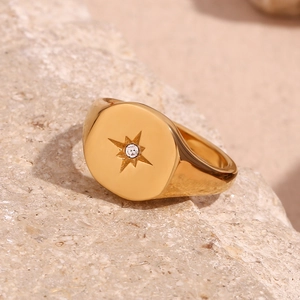 Macro shot of 18K gold plated stainless steel signet ring with starburst and gem detail