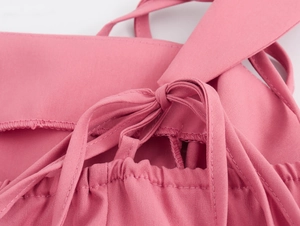 Détail de la robe rose montrant les bretelles réglables nouées en nœud de papillon