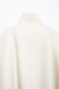 Close-up of elegant white blend fabric texture and stand-up collar design on the coat