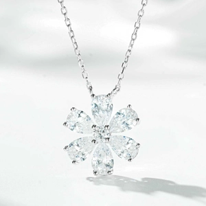 Détail macro d'un pendentif fleur en argent avec des pierres claires taillées en poire