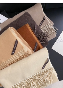 Stacked collection of soft fringe scarves in beige, camel, caramel, and coffee brown