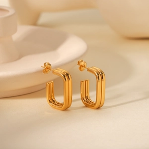 Detailed view of gold rectangle double-line earrings on minimalist ceramic display