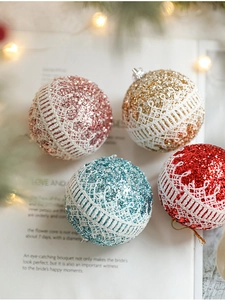 Close-up of glittery Christmas balls with white lace trim on vintage book pages