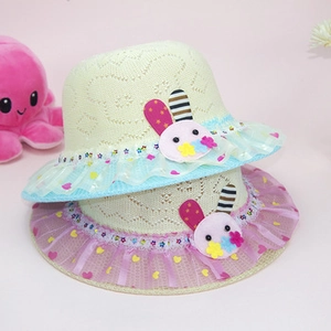 Detail of child's straw hat with lace trim and cute rabbit patch on pink background