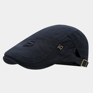 Detail view of the navy cotton flat cap showing the KS metal logo and side embroidery