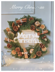 Detail of Christmas wreath with pine needles, cinnamon sticks, orange slices and Merry Christmas sign