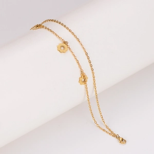 Elegant gold double-layer stainless steel anklet with two delicate flower charms on a stand