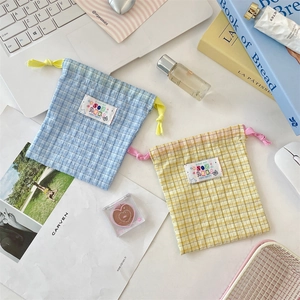 Detail of checkered drawstring storage bags in blue and yellow with dual rope closure