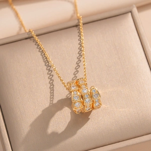 Close-up of gold snake pendant with inlaid crystals inside a beige jewelry box