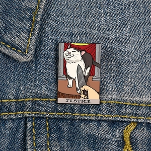 Enamel Justice Cat tarot card brooch featuring a sad cat meme on denim jacket