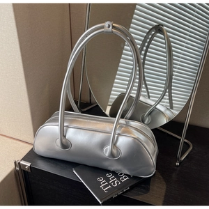 Silver metallic baguette shoulder bag detail on black surface with mirror reflections