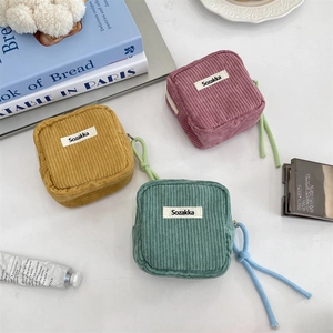 Close-up of corduroy makeup bags in yellow, pink and green with long cotton rope pullers