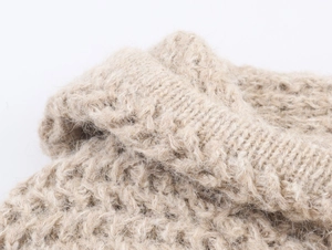 Close-up of thick knit beige fabric showing soft wool texture and heavy needlework