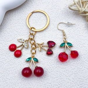 Detailed macro view of red cherry alloy pendants with gold plating and green leaf accents