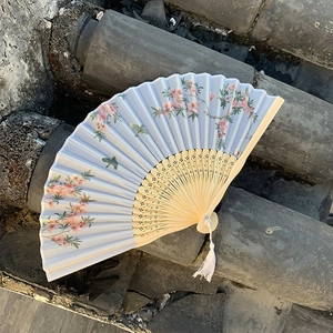 Detailed macro of pink peach blossom pattern on grey silk fan with white tassel