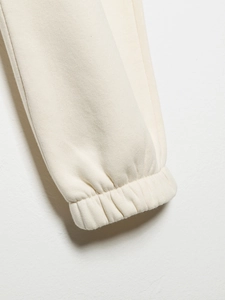 Gros plan des poignets en tricot crème avec détails côtelés élastiques et texture coton doux
