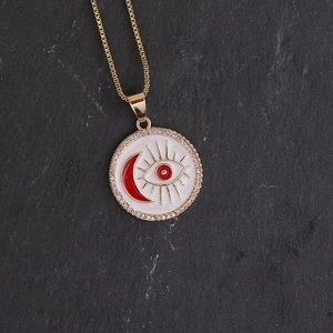 Detailed close-up of 18K gold evil eye pendant with moon and white enamel on stone