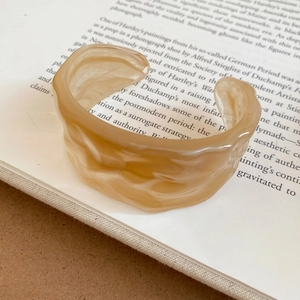 Detailed view of an irregular wavy acrylic bangle on an open book background