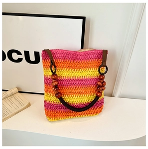 Detail of colorful woven straw bag featuring pink, orange, and yellow stripes with wood beads