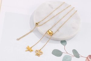 Détail du collier en titane doré avec breloques cœur, libellule et papillon