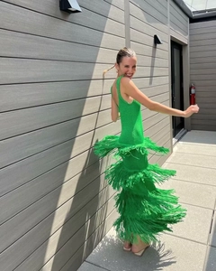 Détail dynamique des franges vertes superposées sur la robe en tricot au soleil