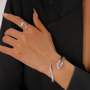 Close-up of sleek silver snake jewelry set with a matching open ring and bracelet on model