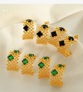 Détail macro de boucles d'oreilles en C plaquées or avec motif de grille et zircons