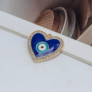 Detail of a heart-shaped Evil Eye pendant with blue resin and sparkling white crystals