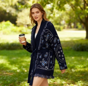 Detail view of navy blue knit cardigan featuring intricate white paisley jacquard and fringes