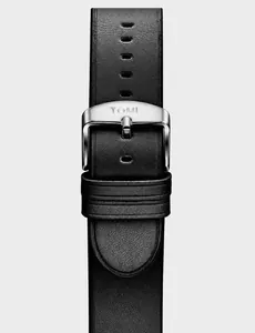 Detail of black leather watch strap with matte silver buckle and engraved TOMI logo