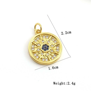 Detail view of gold sunburst pendant with blue stone, 2.2cm height and 1.6cm width