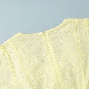 Detailed view of yellow cotton dress featuring floral eyelet embroidery and a hidden zipper