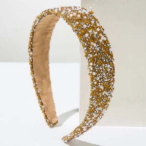 Close-up of luxury gold headband featuring faux pearls and crystals on a white pedestal