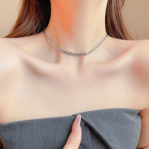 Close-up of a minimalist silver square link chain necklace worn on the collarbone