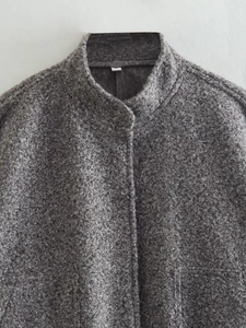 Close-up of the dark grey textured boucle fleece fabric and stand collar jacket detail