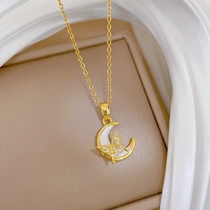 Detail of gold crescent moon pendant with shell inlay and crystal butterfly on silk