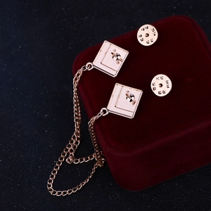 Golden geometric square collar pin with metal chain on a deep red velvet box