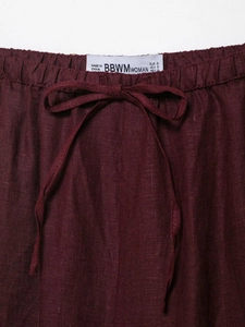 Macro view of elastic waistband and drawstring on burgundy linen blend trousers